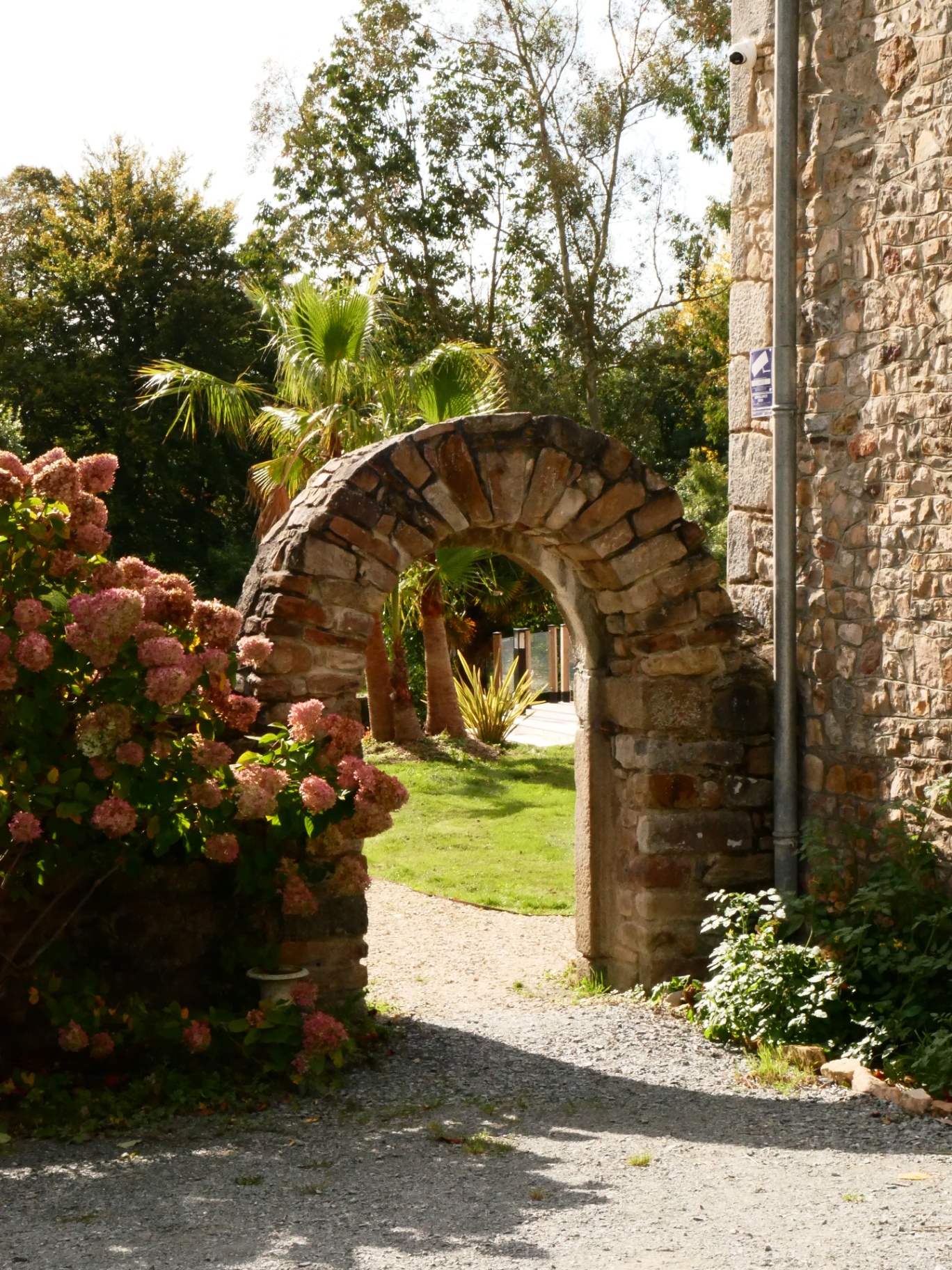 Arche de pierre et hortensias à l'entrée du domaine